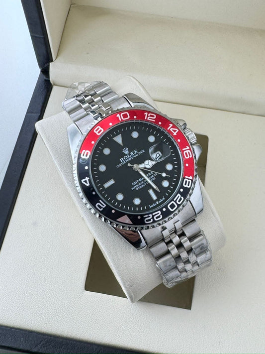Rolex watch with black face and red bezel on a white cushion